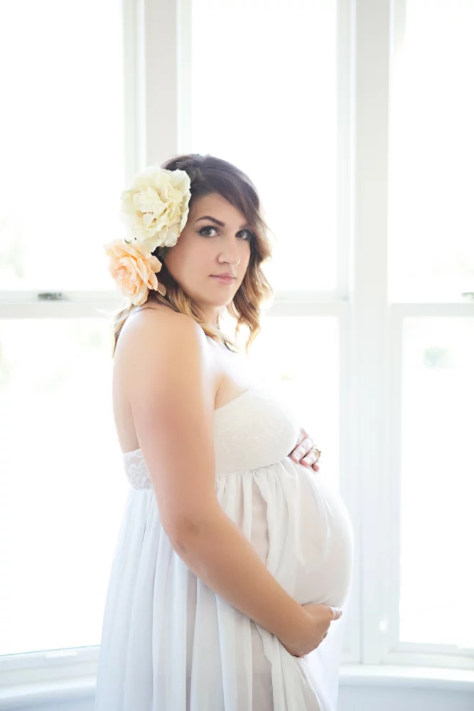 Image of flowers in hair and white dress studio maternity session
