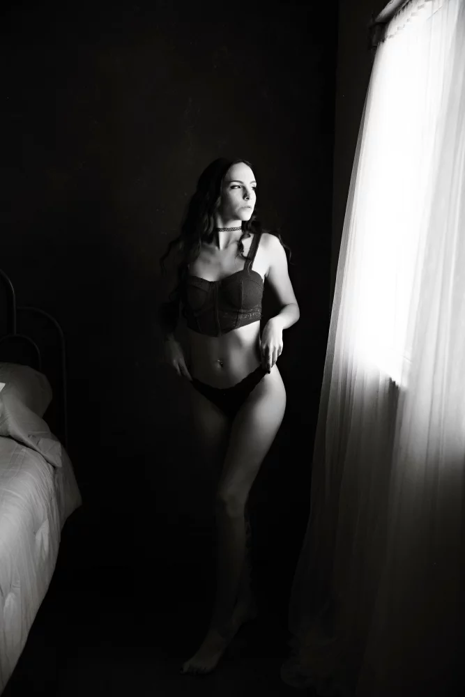 Image of photo of a woman standing by a window looking out
