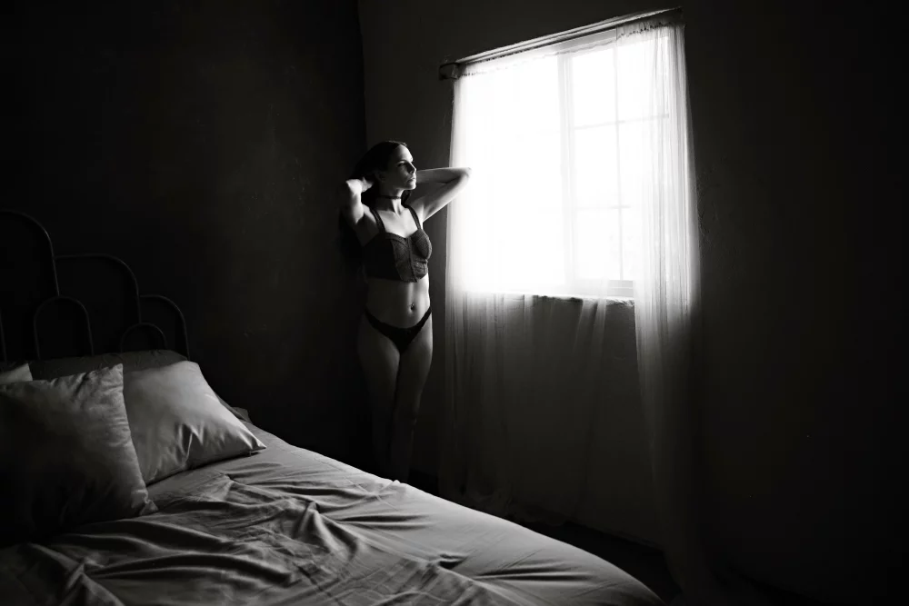 Image of woman standing by a window looking out wearing lingerie